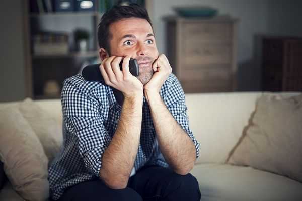 A smiling man intently watching a movie.